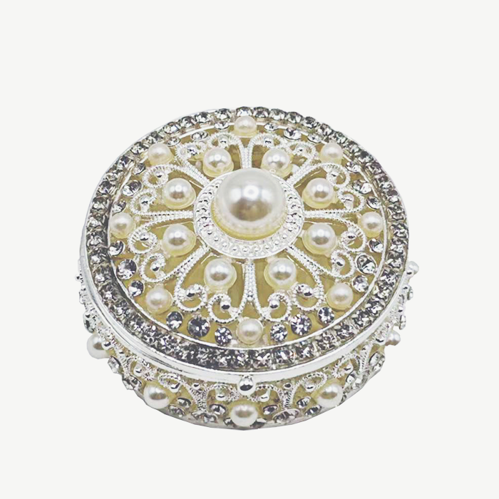 Decorative round box with pearls and crystals on a white background